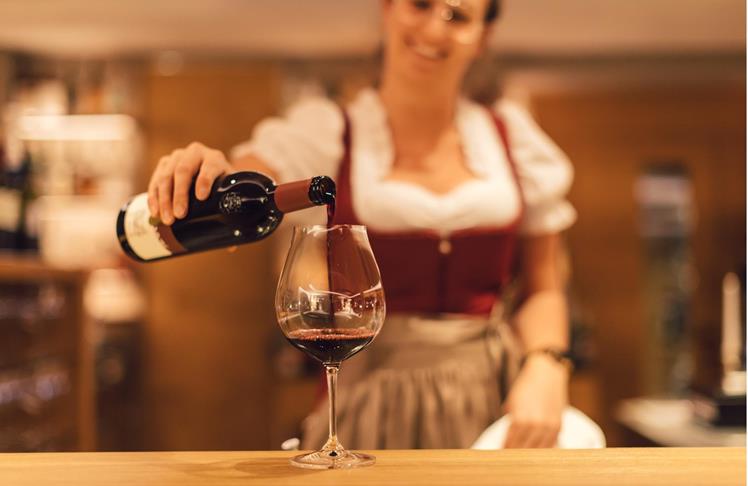 Una cameriera riempe un calice di vino rosso