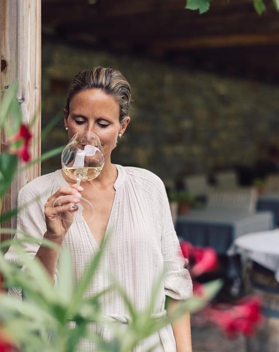 Una donna beve un bicchiere di vino bianco in giardino