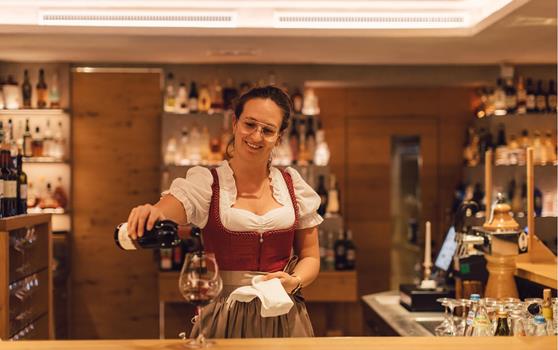 Una cameriera riempie un calice di vino rosso