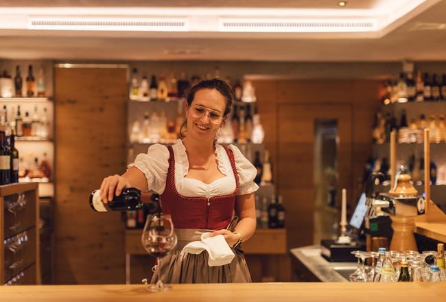 Una cameriera riempie un calice di vino rosso